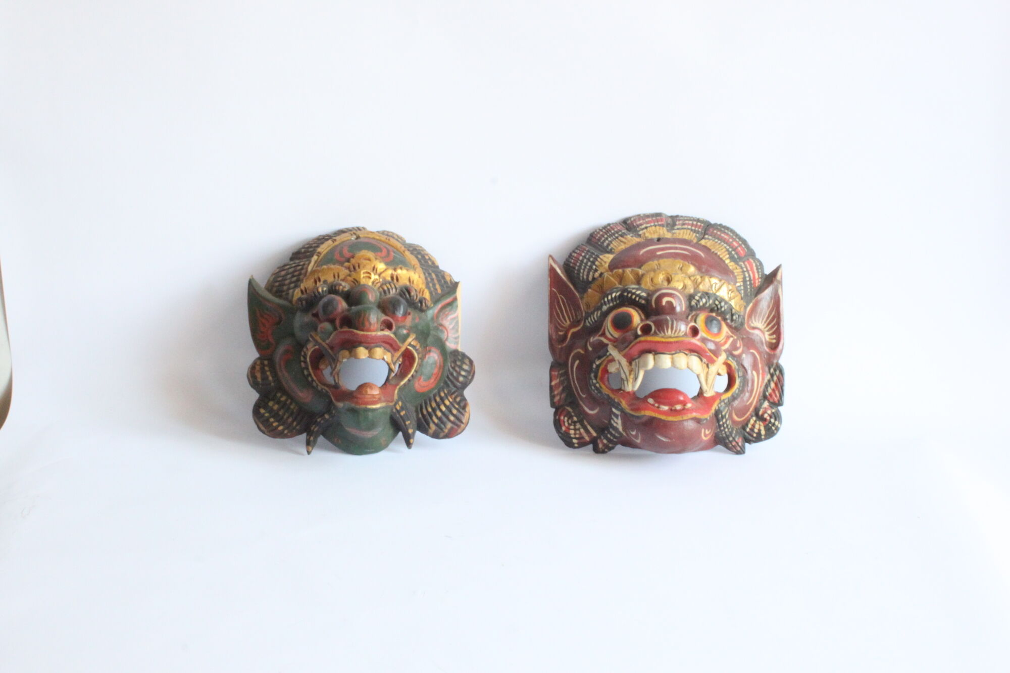 Two polychrome painted and gold leaf gilded Barong dance masks from Bali, Indonesia.