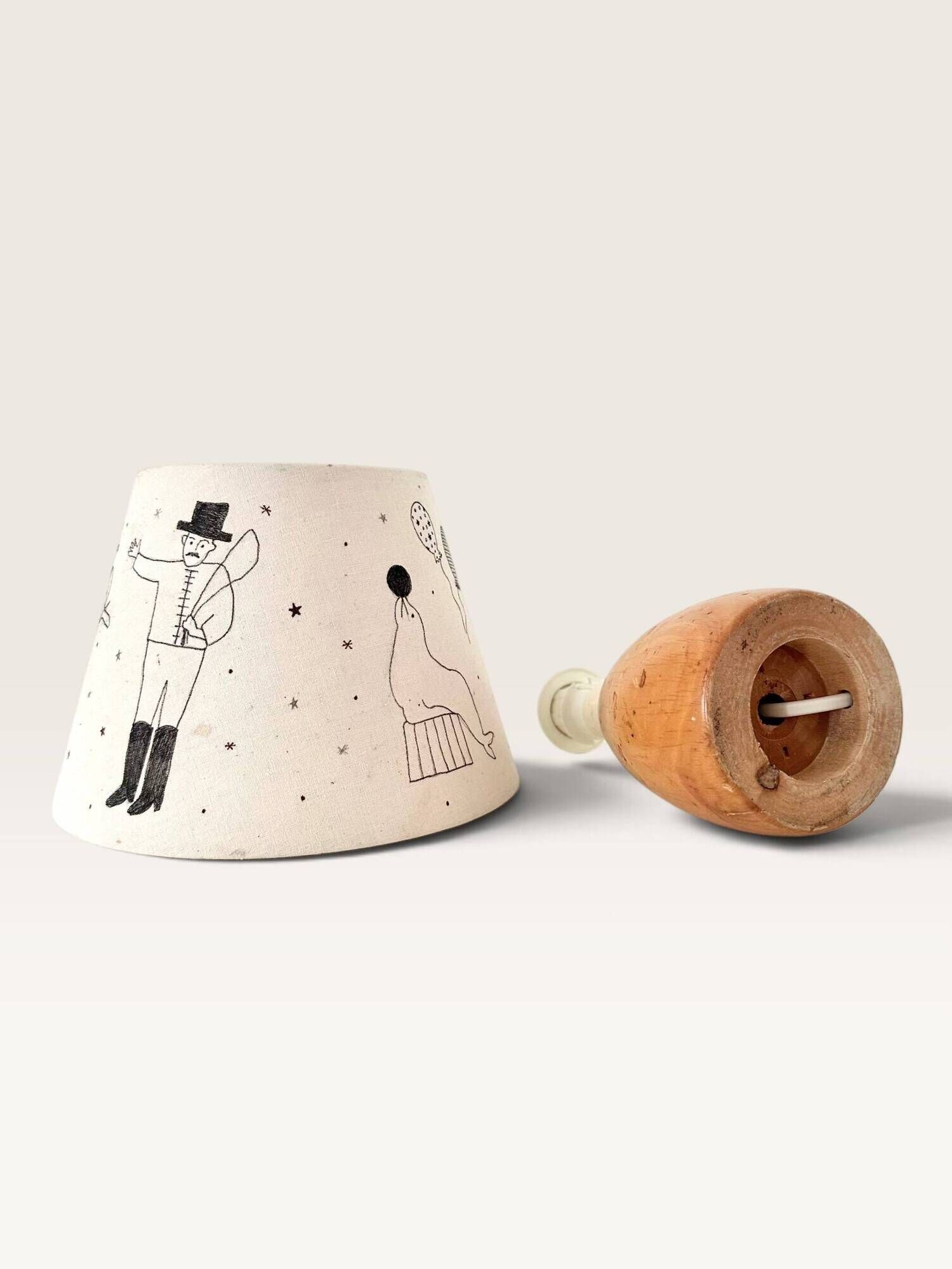 Wood-turned lamp with a hand-drawn lampshade, circus patterns.