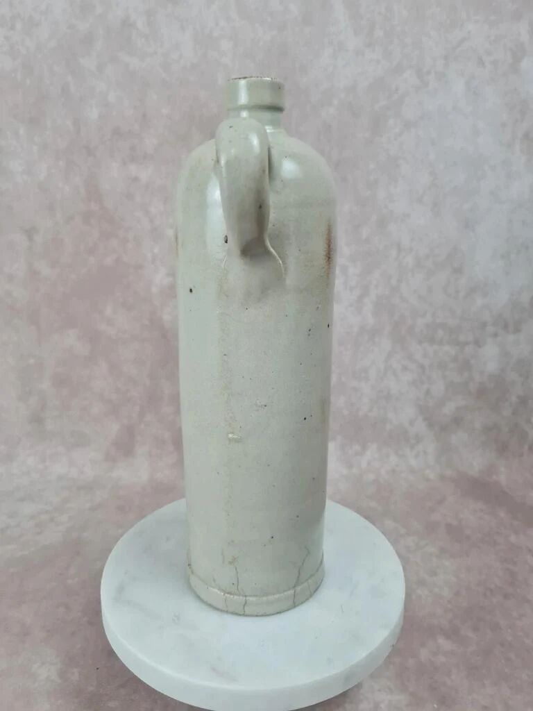 Antique beige glazed stoneware bottle from the 19th century, with a handle, vintage decor.