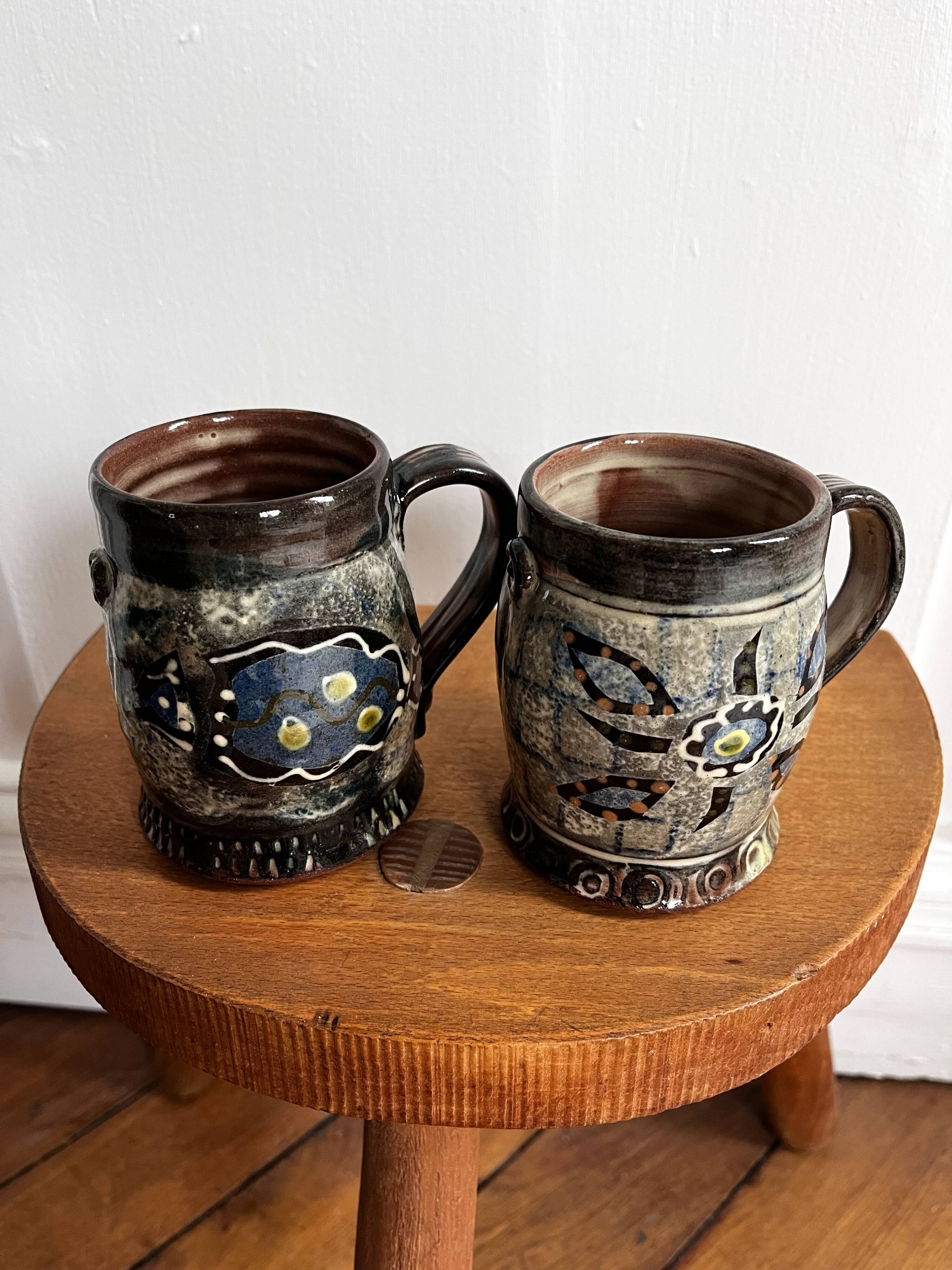 Vintage terracotta mugs with glazed designs and flower/fish motifs