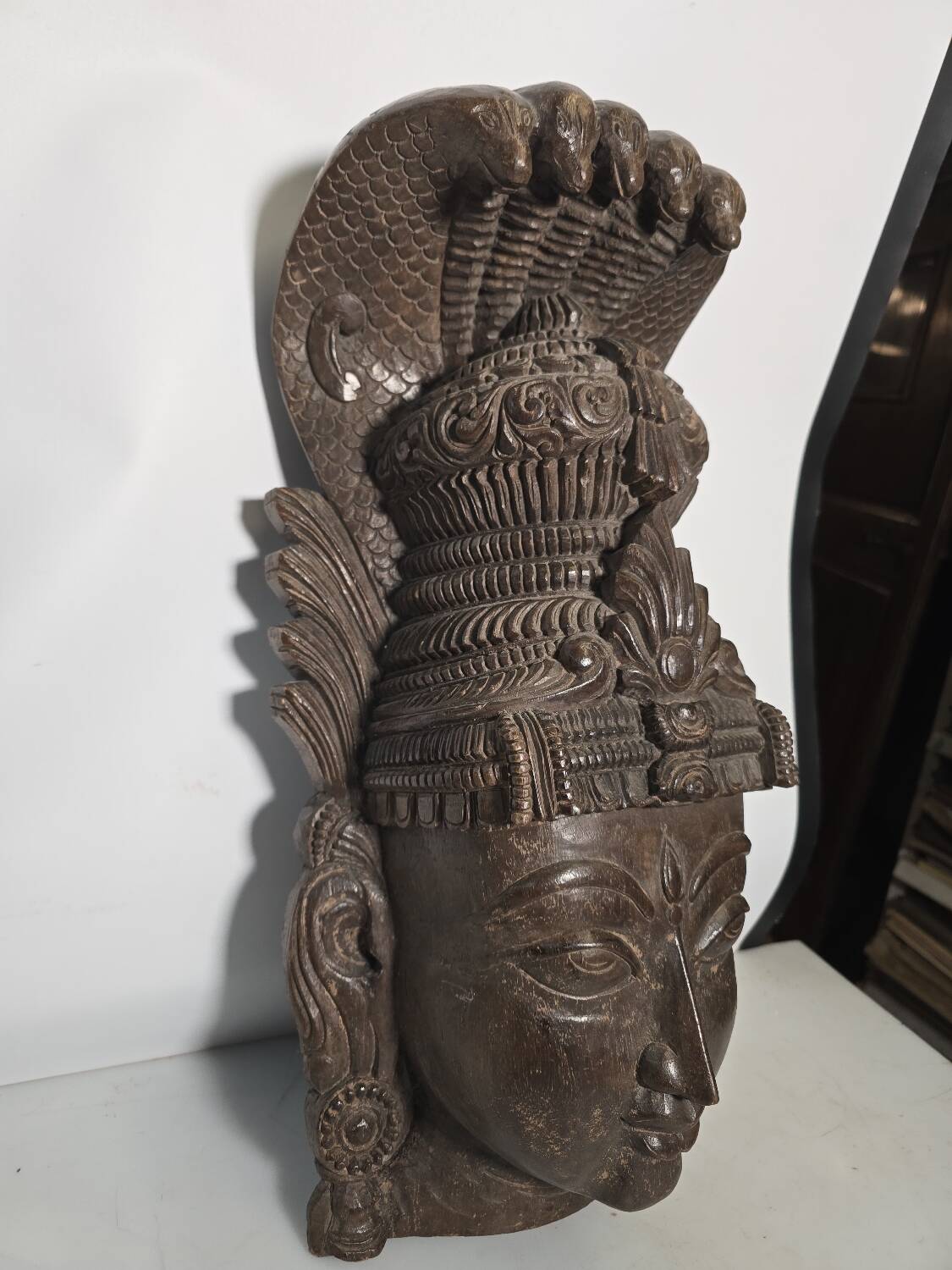 Ancient Indian carved wooden mask sculpture of a deity with a cobra.