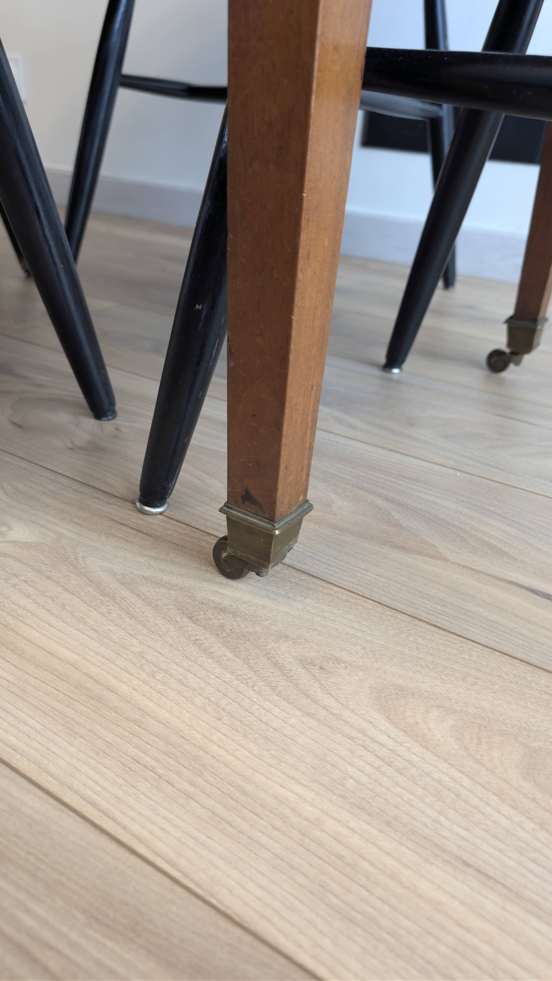 Antique wooden folding table with a patina and brass wheels.