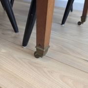 Antique wooden folding table with a patina and brass wheels.
