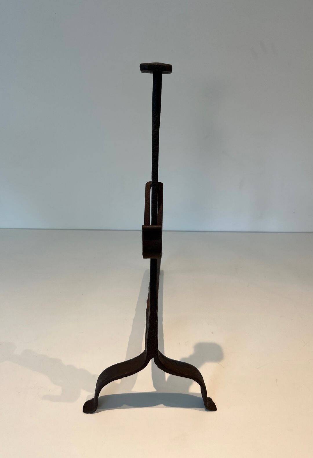 Pair of wrought iron andirons with adjustable supports and tripod feet.