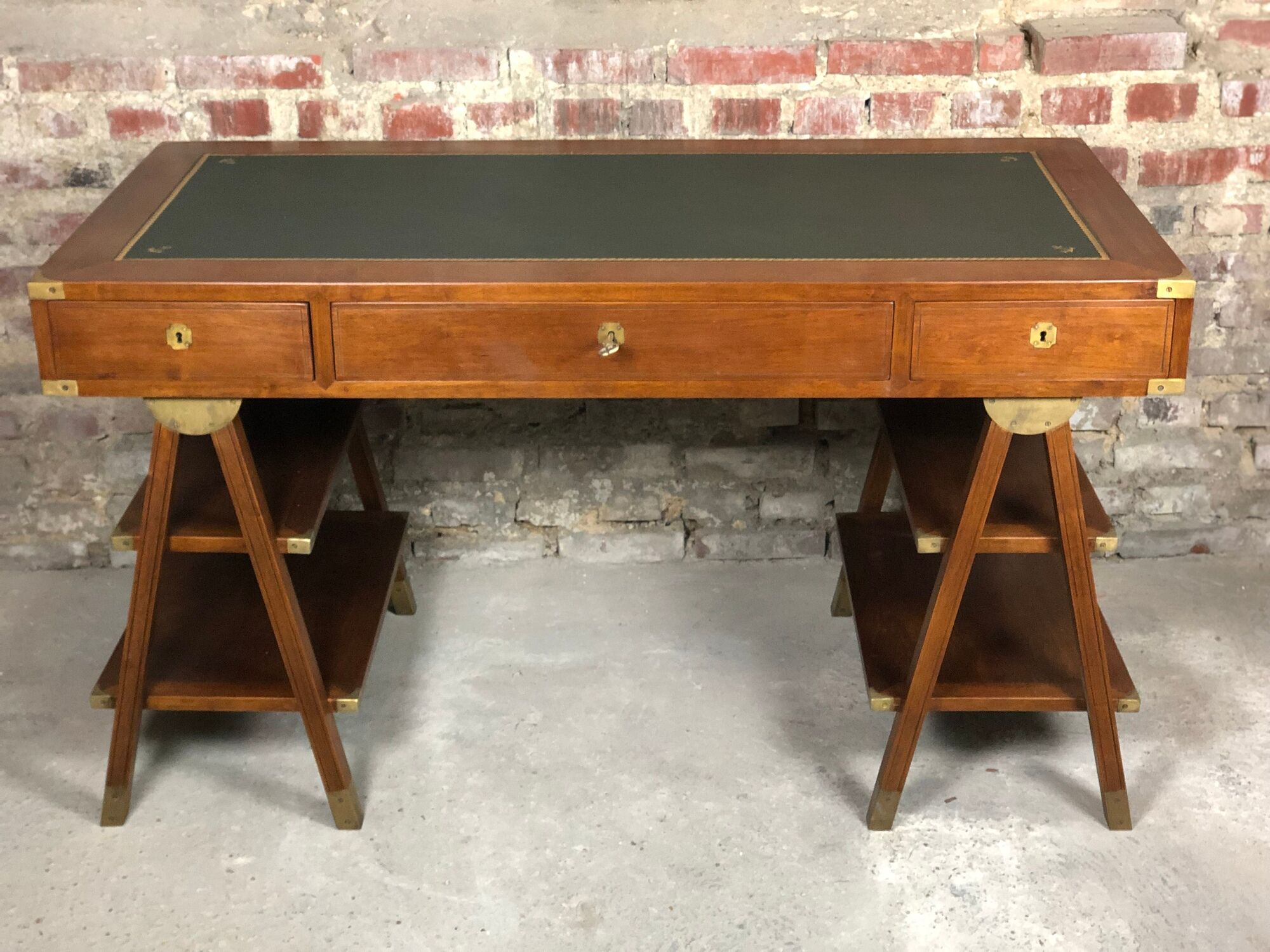 Walnut desk with green leather top resting on two trestles