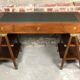 Walnut desk with green leather top resting on two trestles