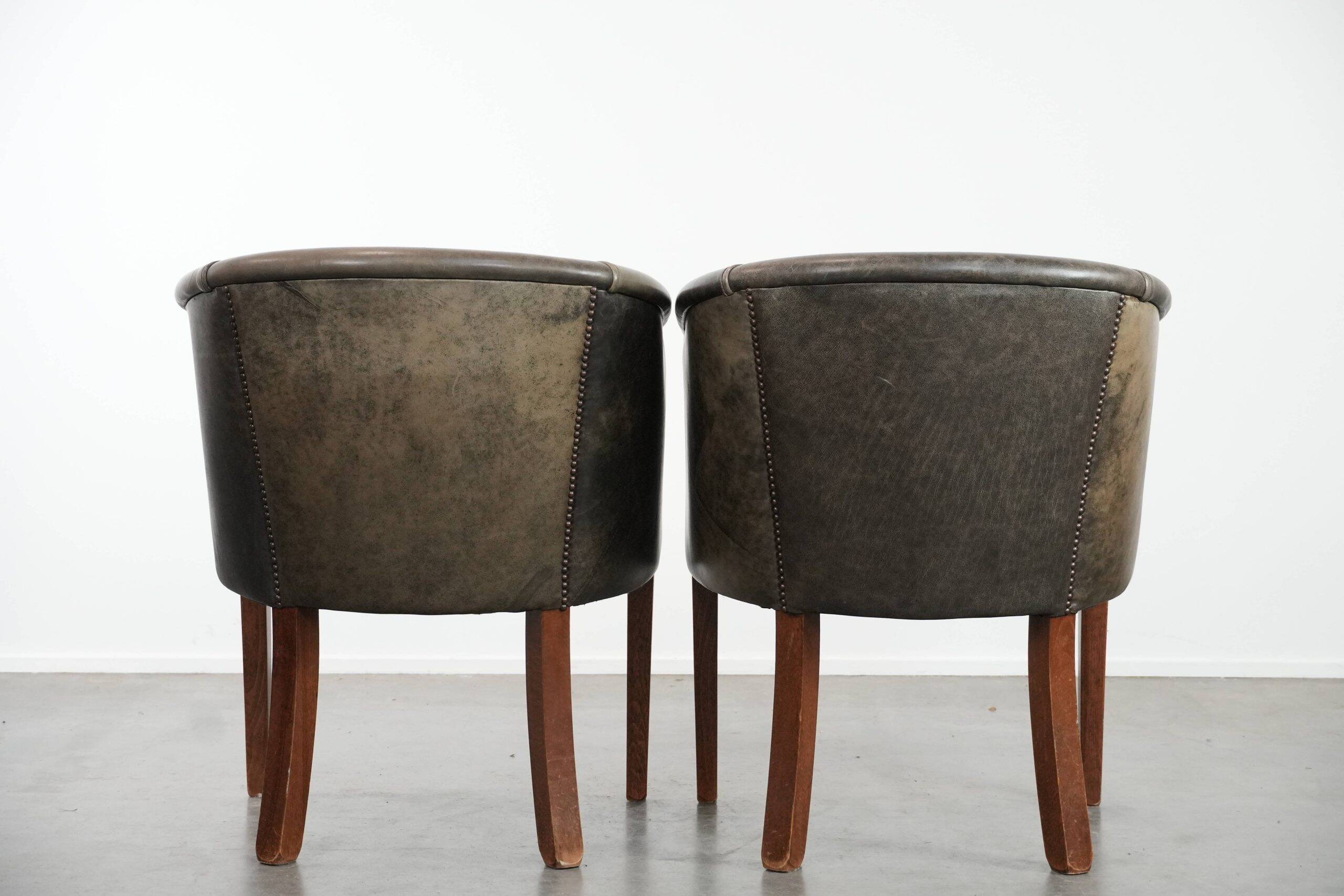 Set of two cowhide and wooden tub chairs with a sturdy colour scheme