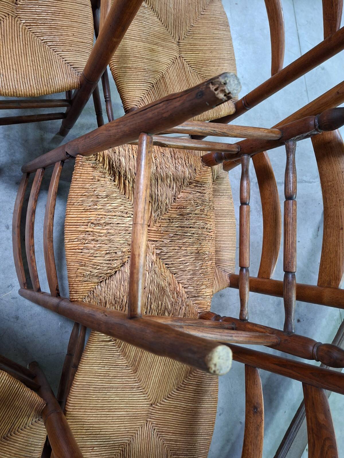 Set of six rustic chairs in natural wood with straw seats.