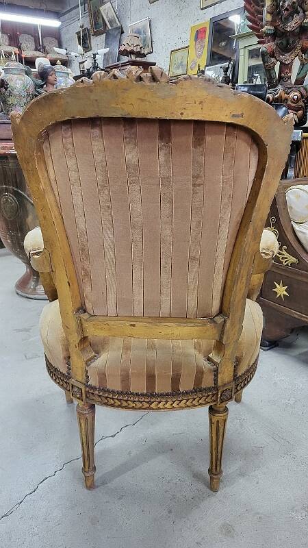 A pair of gilded wooden armchairs in the Louis XVI style.