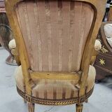 A pair of gilded wooden armchairs in the Louis XVI style.