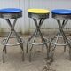 Set of 5 vintage swivel bar stools in blue, red, orange, and yellow.
