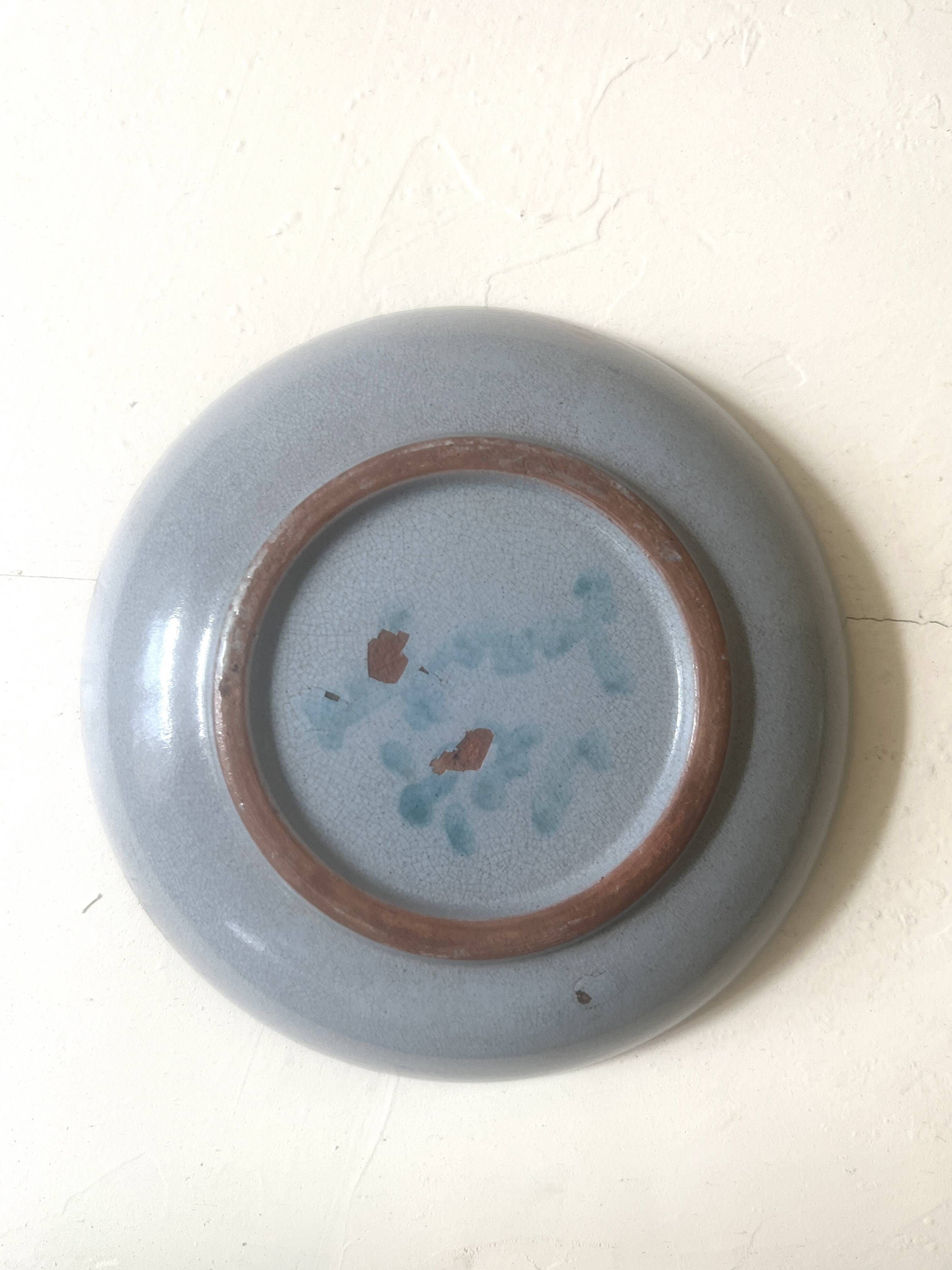 Glazed blue ceramic bowl with stylised fish decoration.