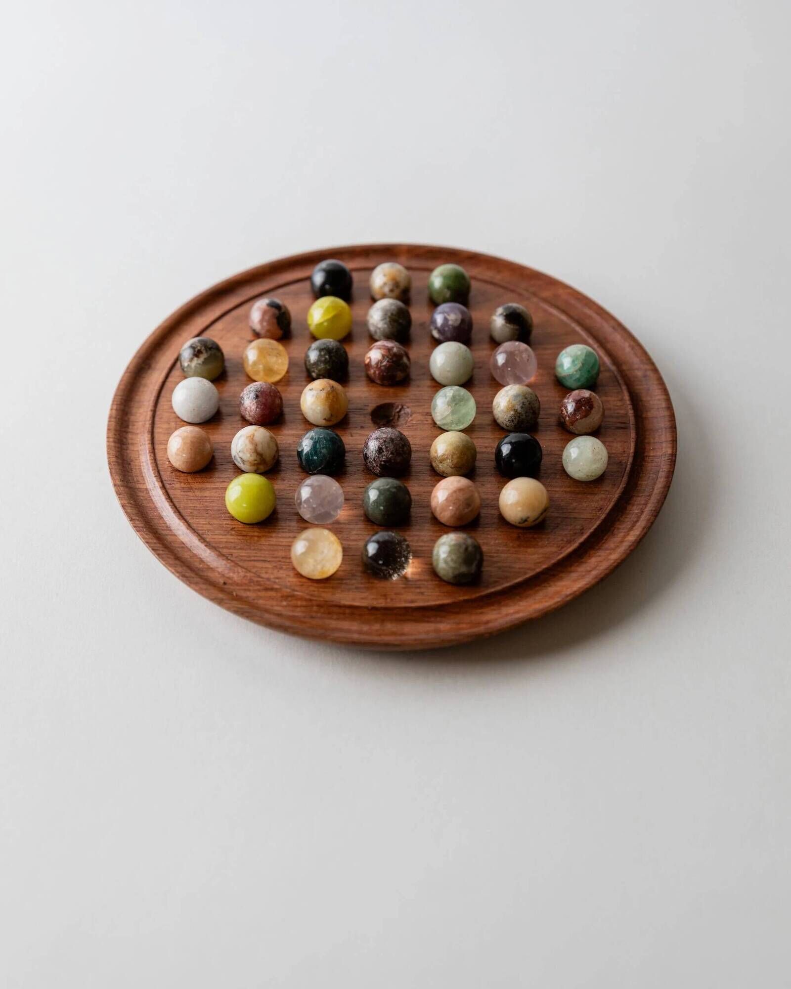 Vintage 1960s solitaire game, wooden board with stone marbles.