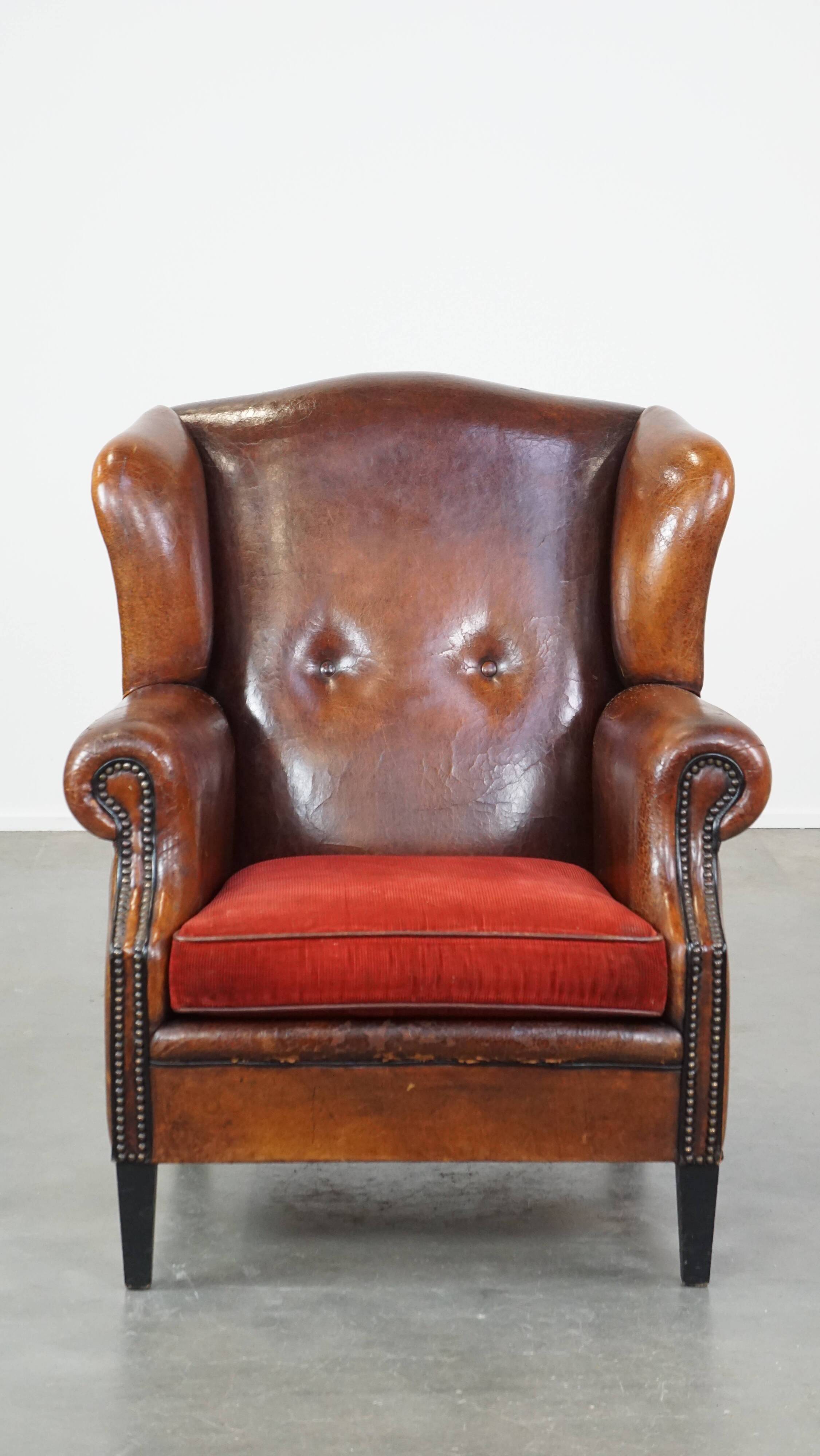 Sheepskin leather wingback chair with a red corduroy seat cushion