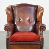 Sheepskin leather wingback chair with a red corduroy seat cushion