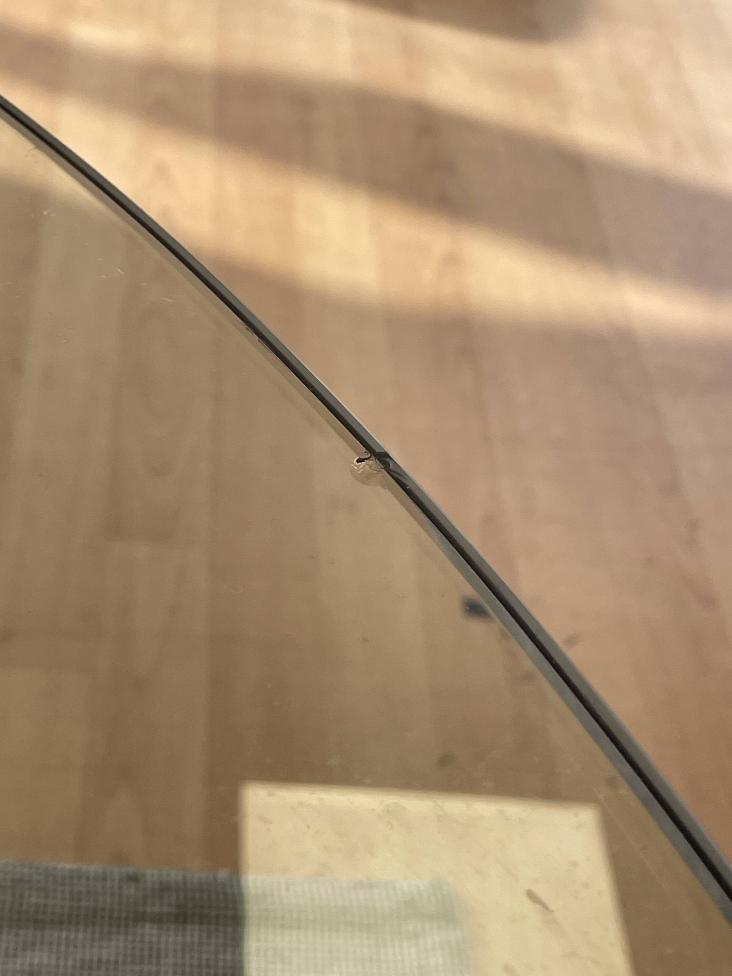 Round dining table with a glass top and brushed metal triangular frame.