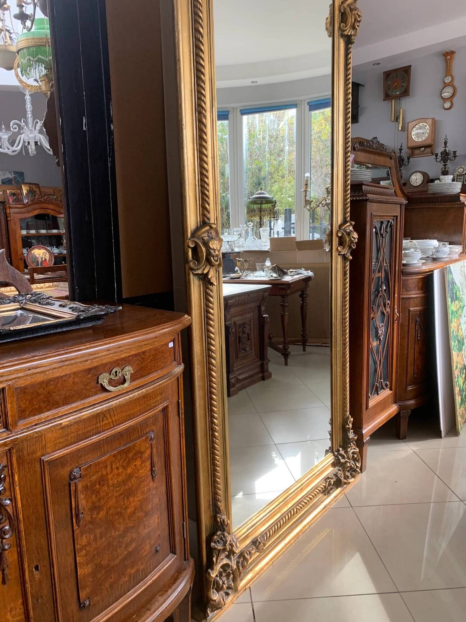 French palace mirror with bow and lion heads, gilded frame.