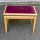 Adjustable piano stool in light beech and purple velvet.