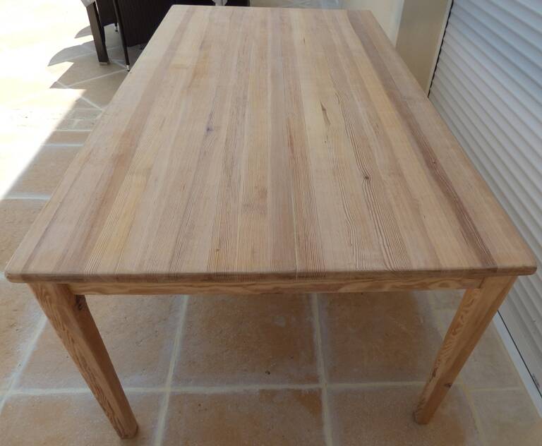 Large natural wood table with rectangular top supported by legs