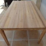 Large natural wood table with rectangular top supported by legs