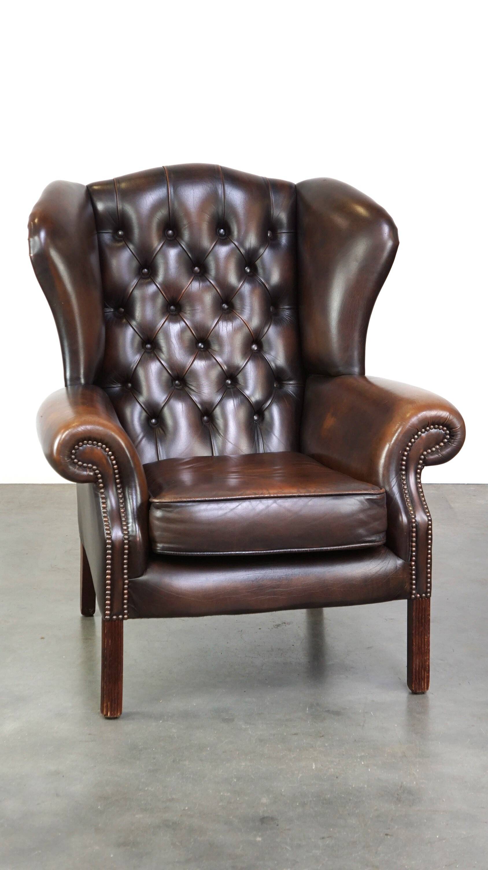 Chesterfield wing chair in dark brown leather with a luxurious appearance