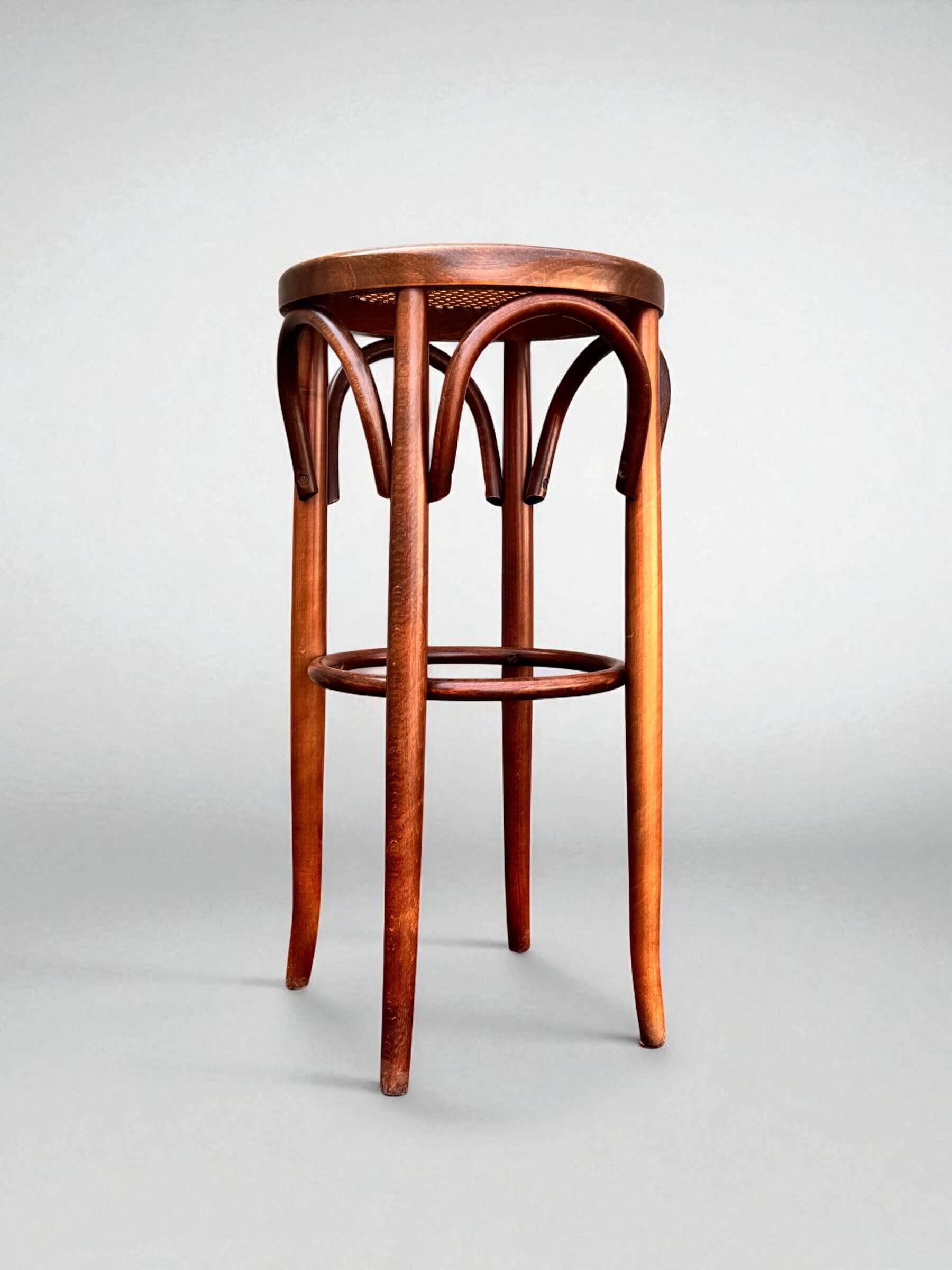 Old high stool in curved wood with caned seat