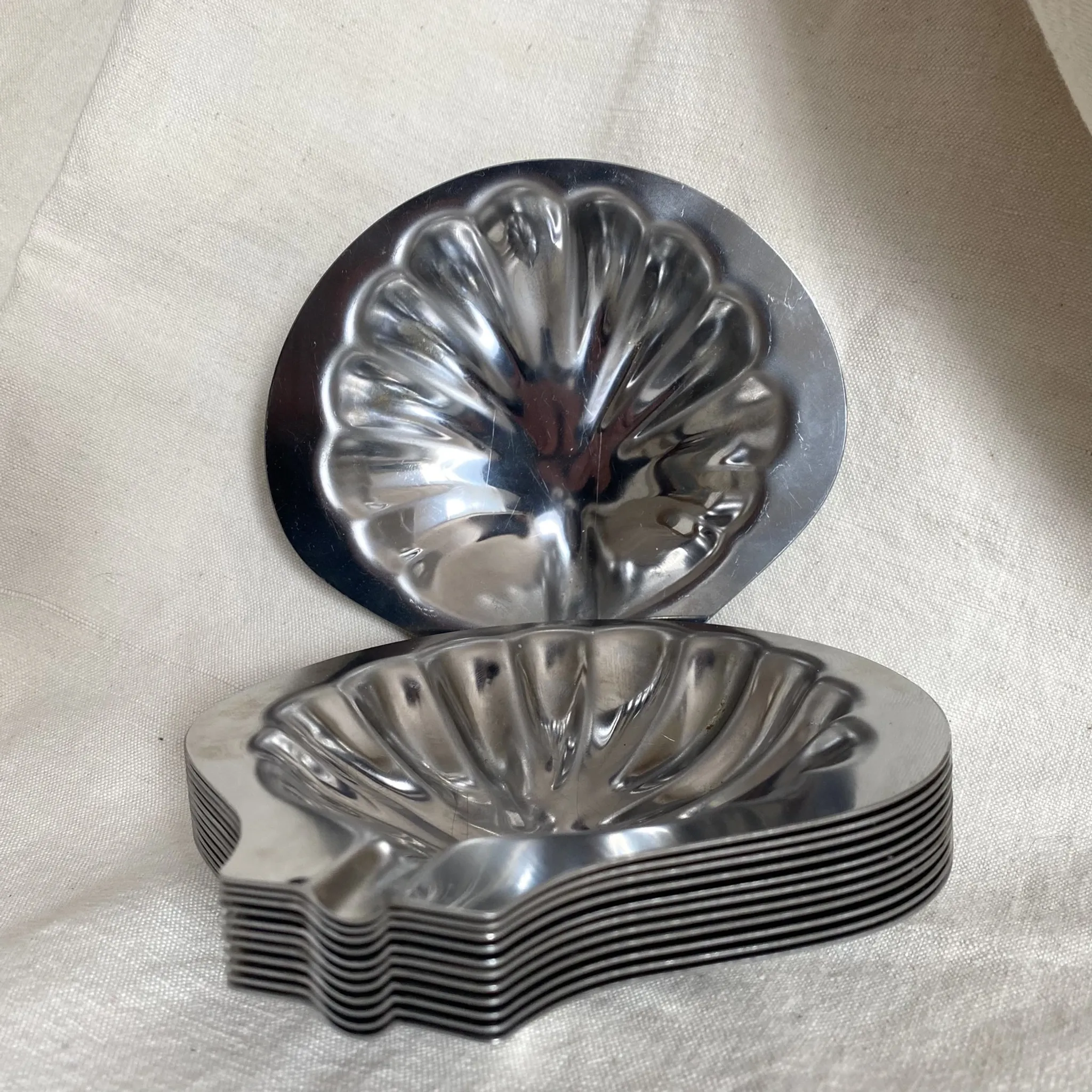 Set of 12 stainless steel scallop shells, 1970s-80s.