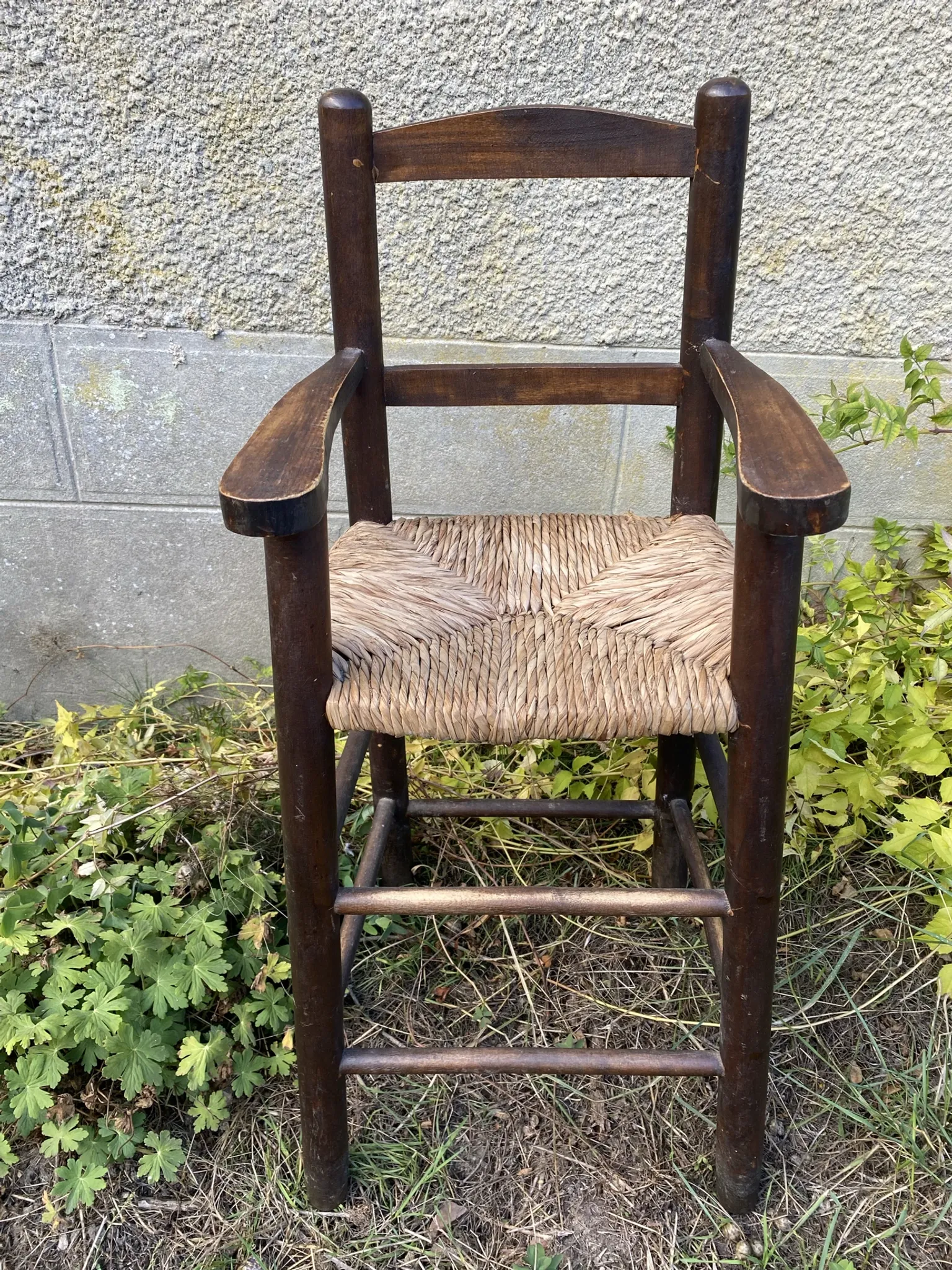 Vintage wooden children's high chair with straw.
