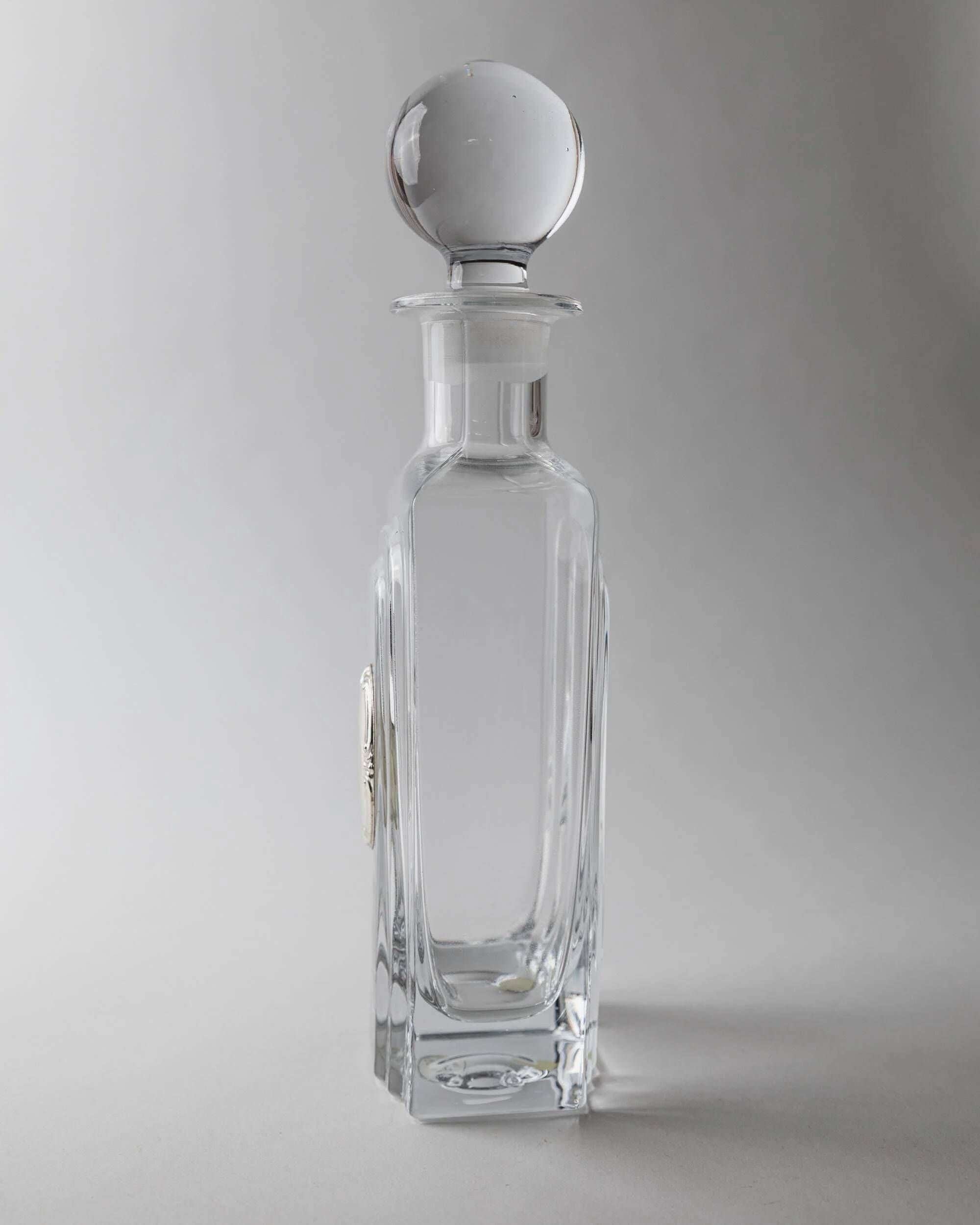 Vintage glass decanter from the 1980s, transparent glass with a silver plate and spherical stopper.