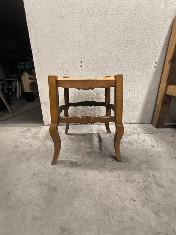 Rustic wooden stool with a straw seat.