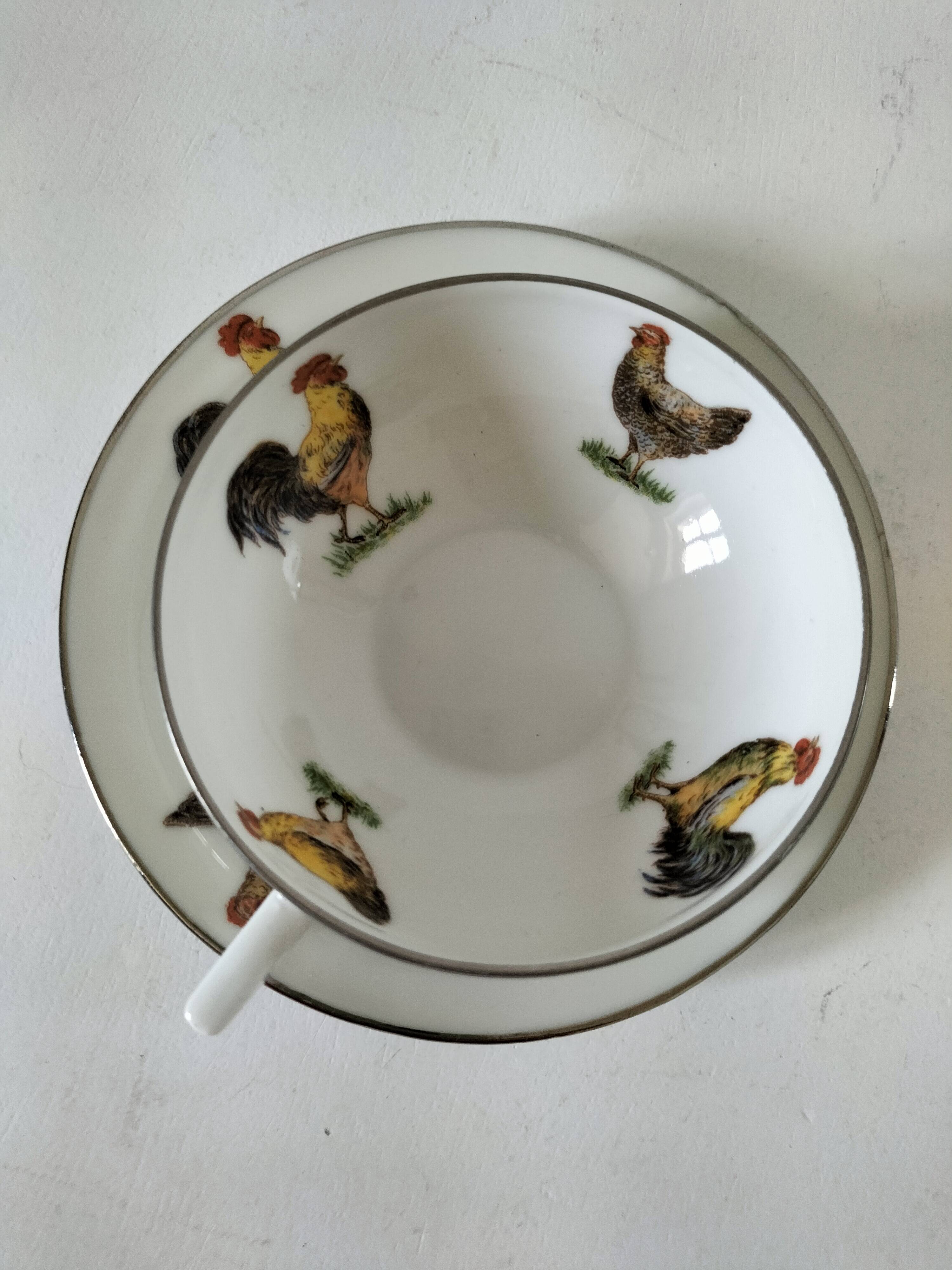 Cup and saucer in porcelain decorated with roosters and hens.
