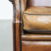 Cognac-colored sheep leather wingback chair finished with black piping