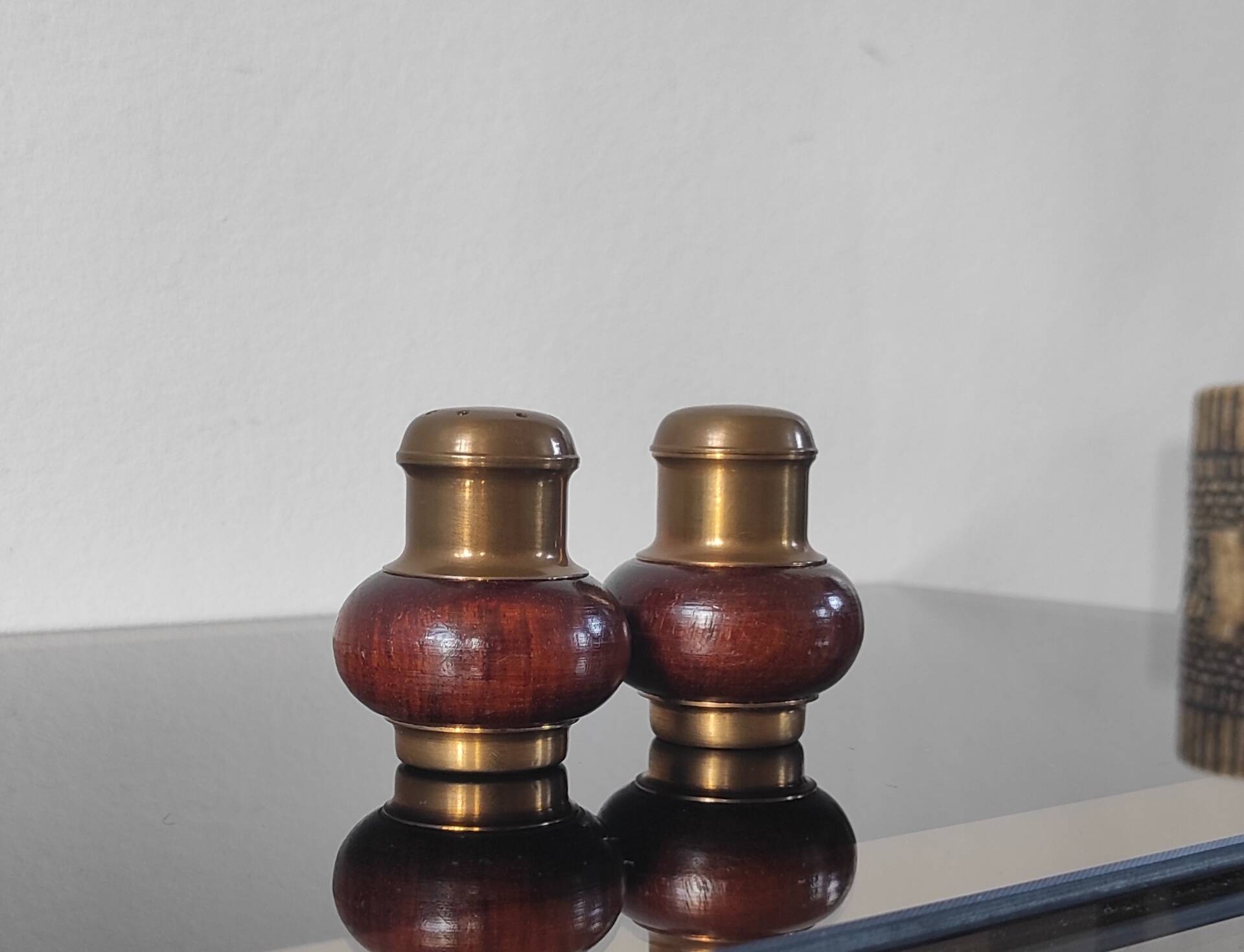 Vintage salt and pepper shaker duo in brass and turned wood.