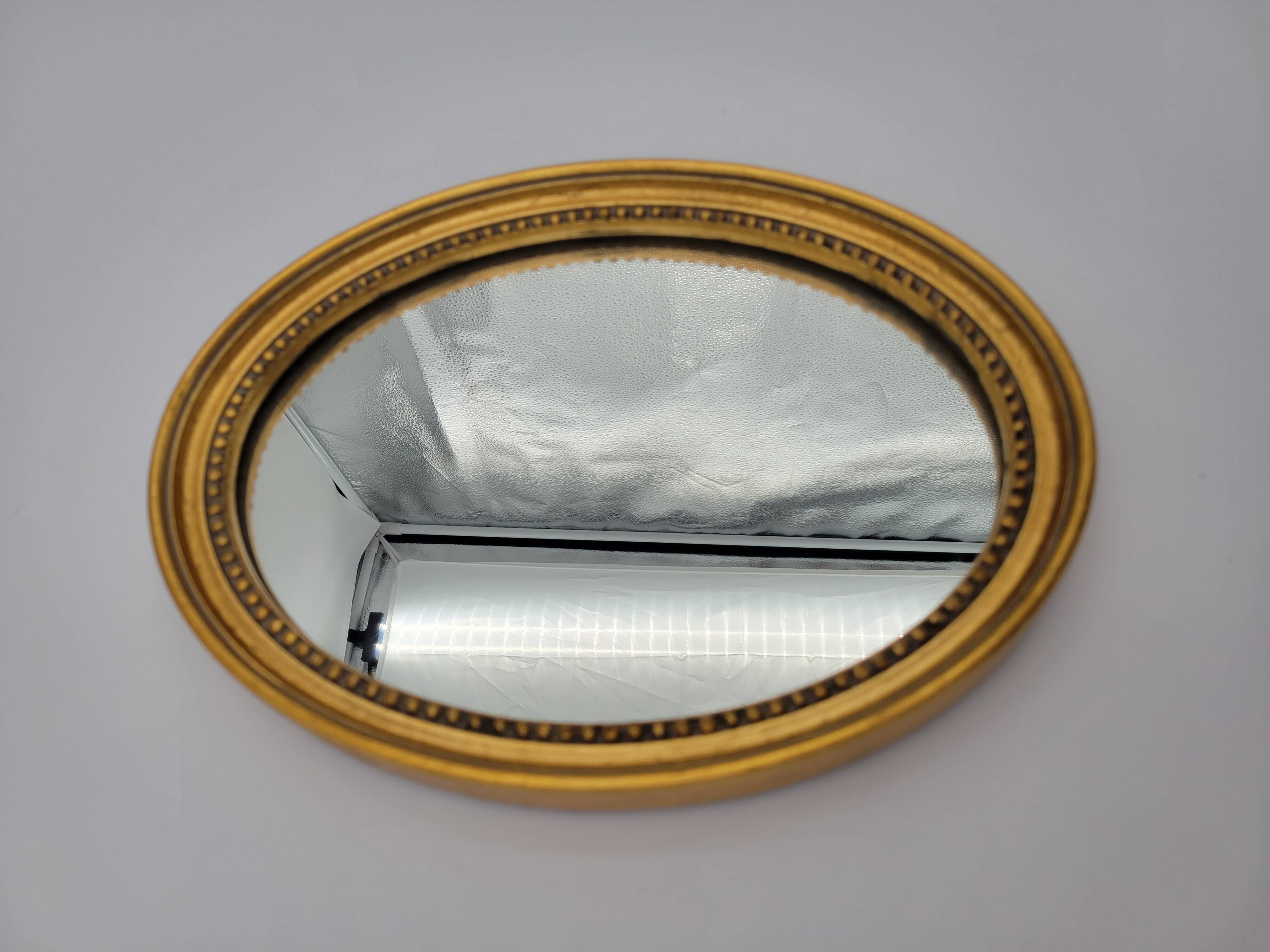 Small old oval mirror in gilded wood
