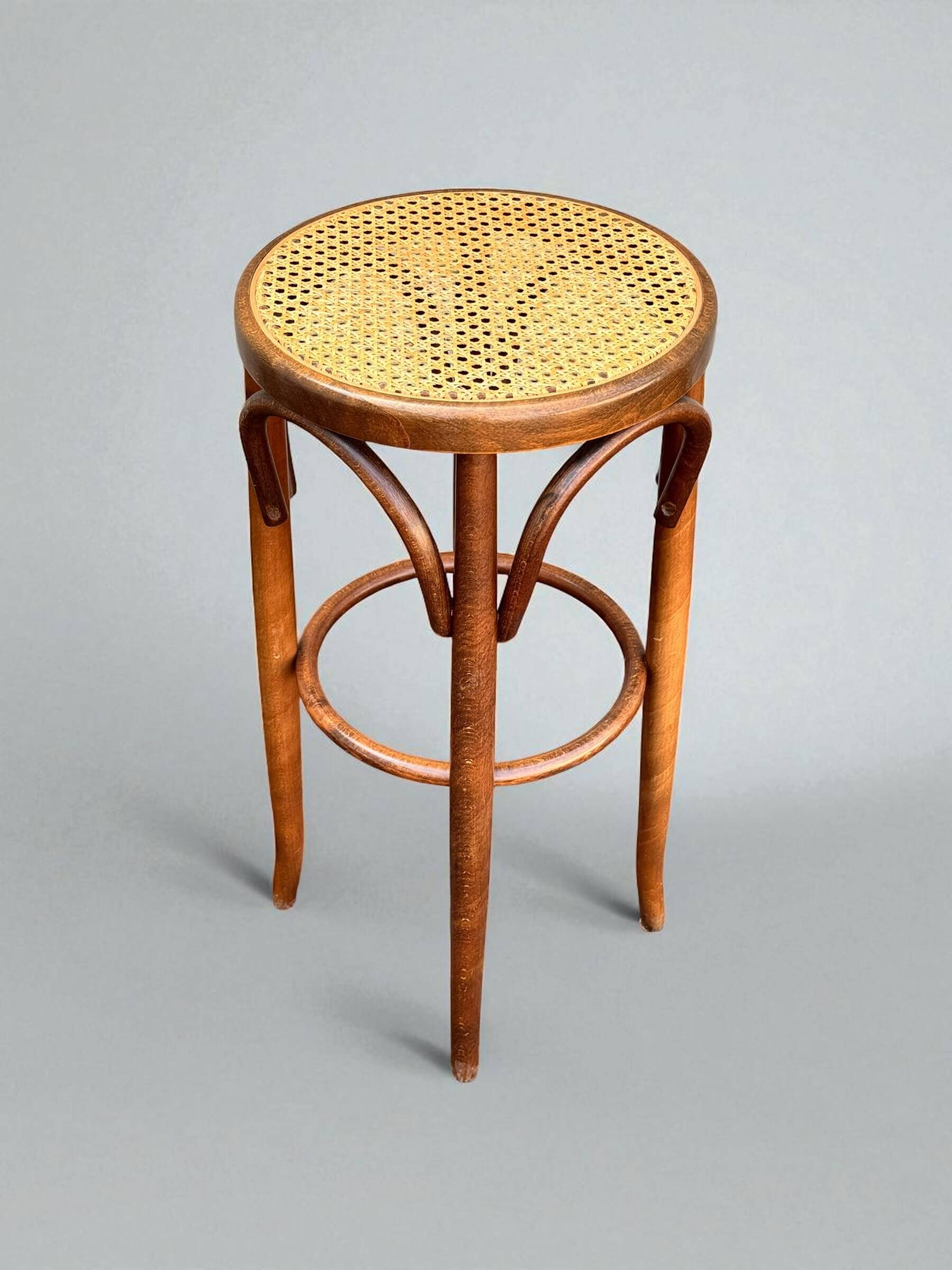 Old high stool in curved wood with caned seat