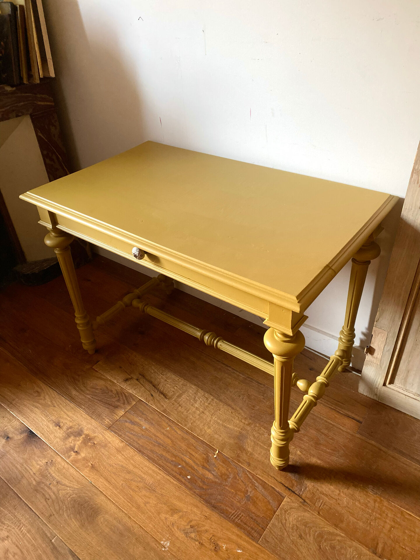 Desk table from the late 19th century, painted mustard, with turned stretcher.