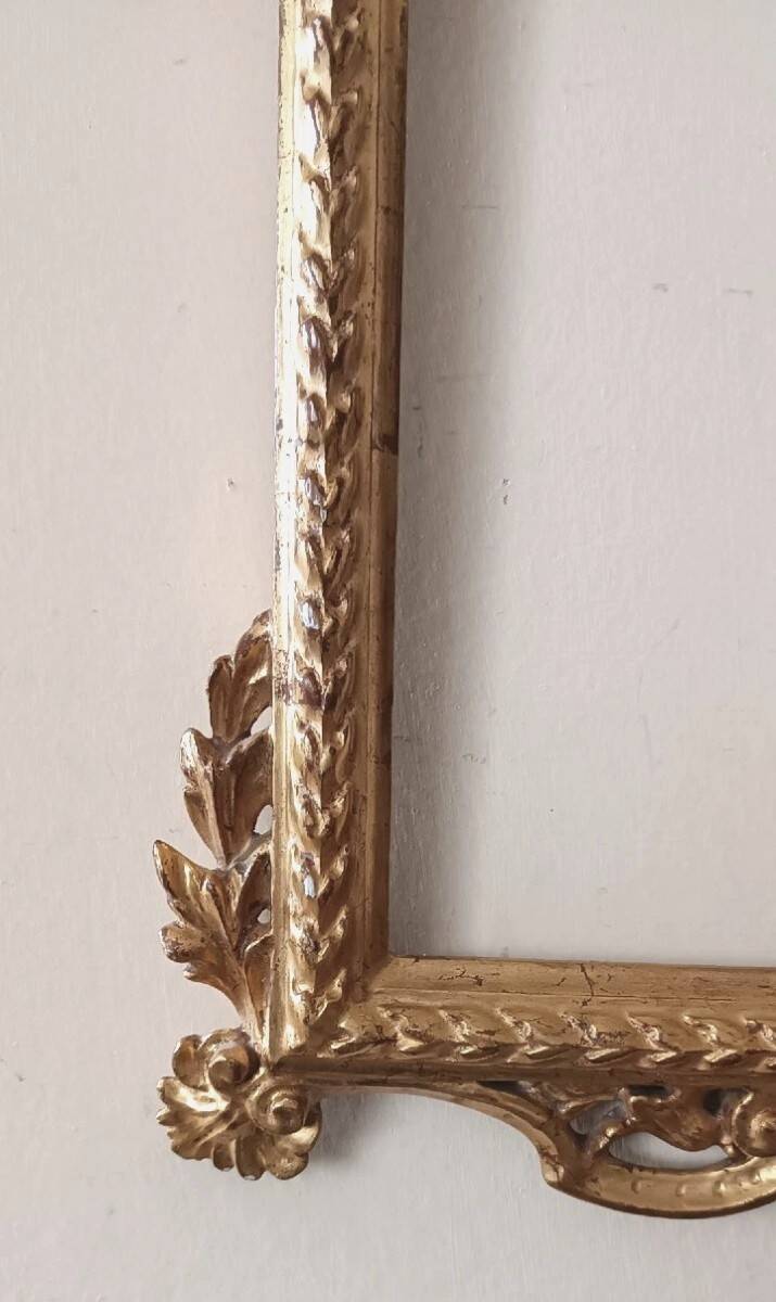 Mirror with a carved wooden frame in an antique style in pure gold.