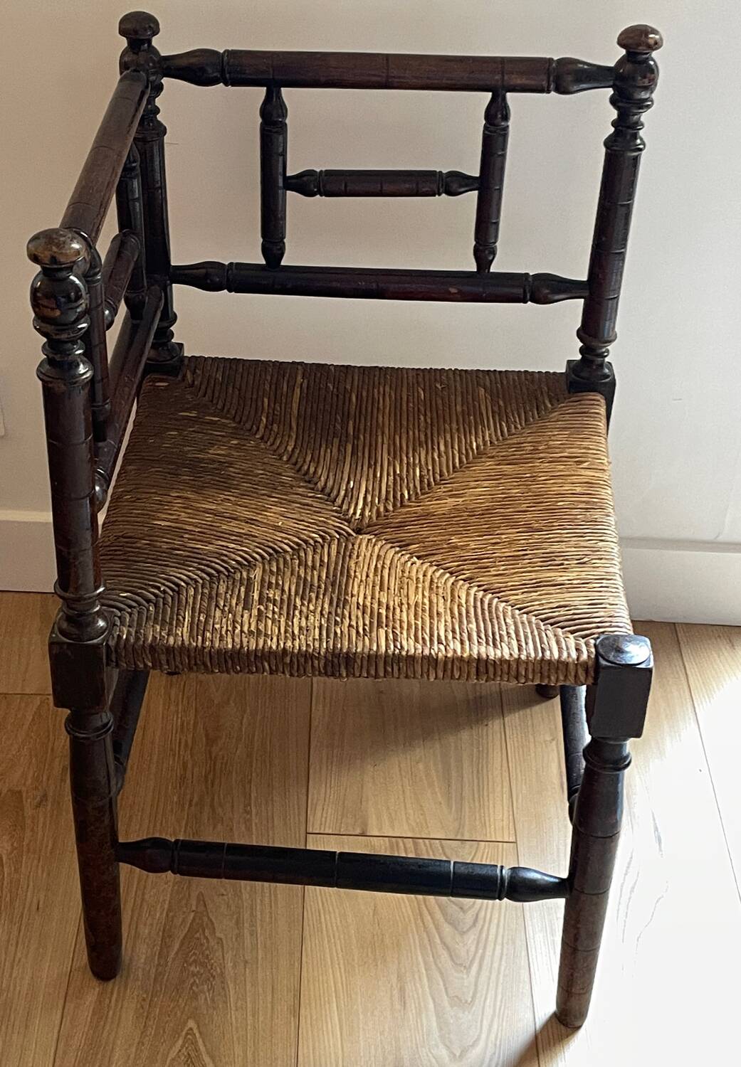 Corner chair made of turned wood with a straw seat.