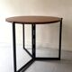 Modernist round folding dining table in wood and metal.