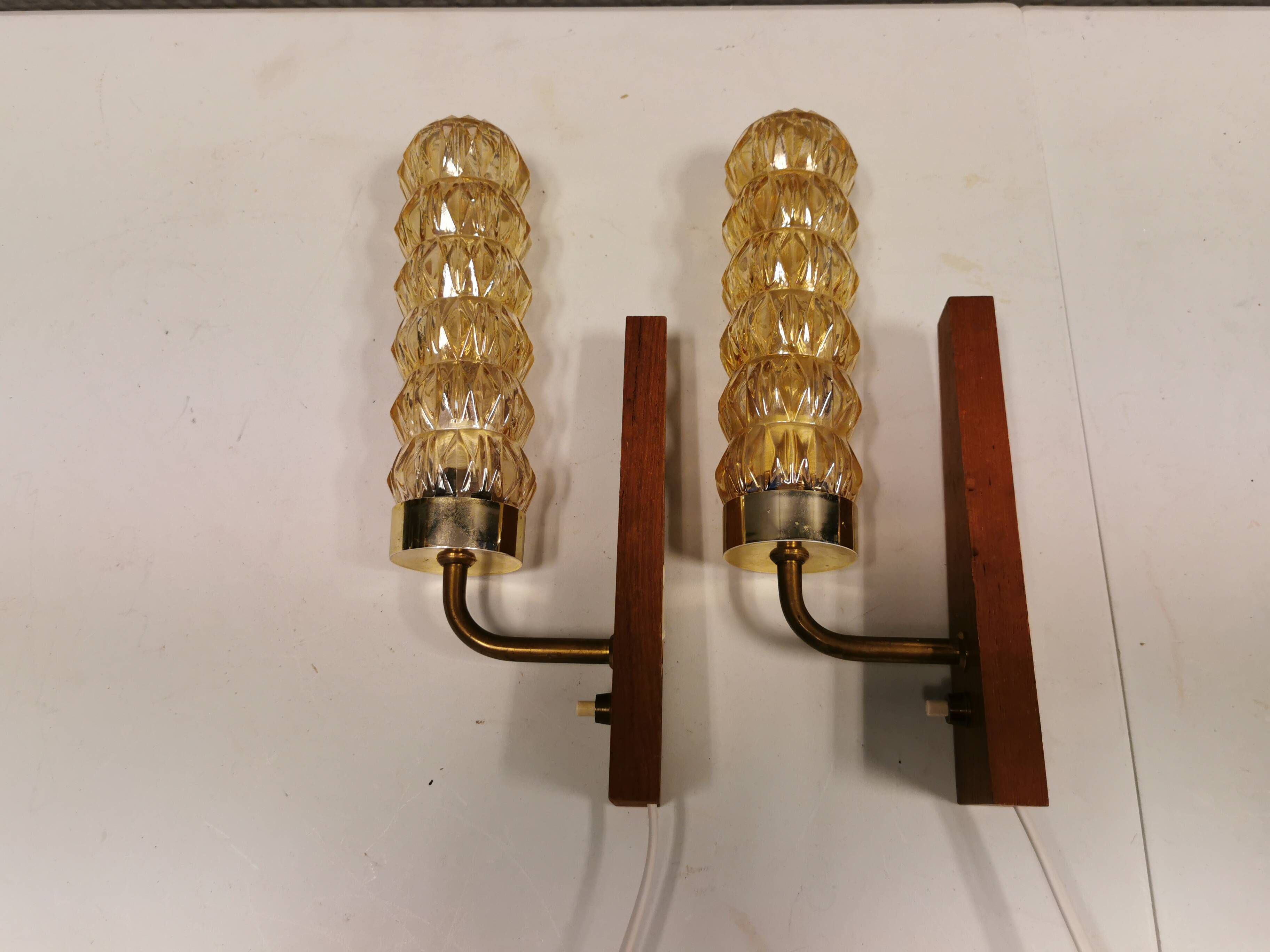 A set of Danish wall lights in champagne coloured glass with brass and teak.