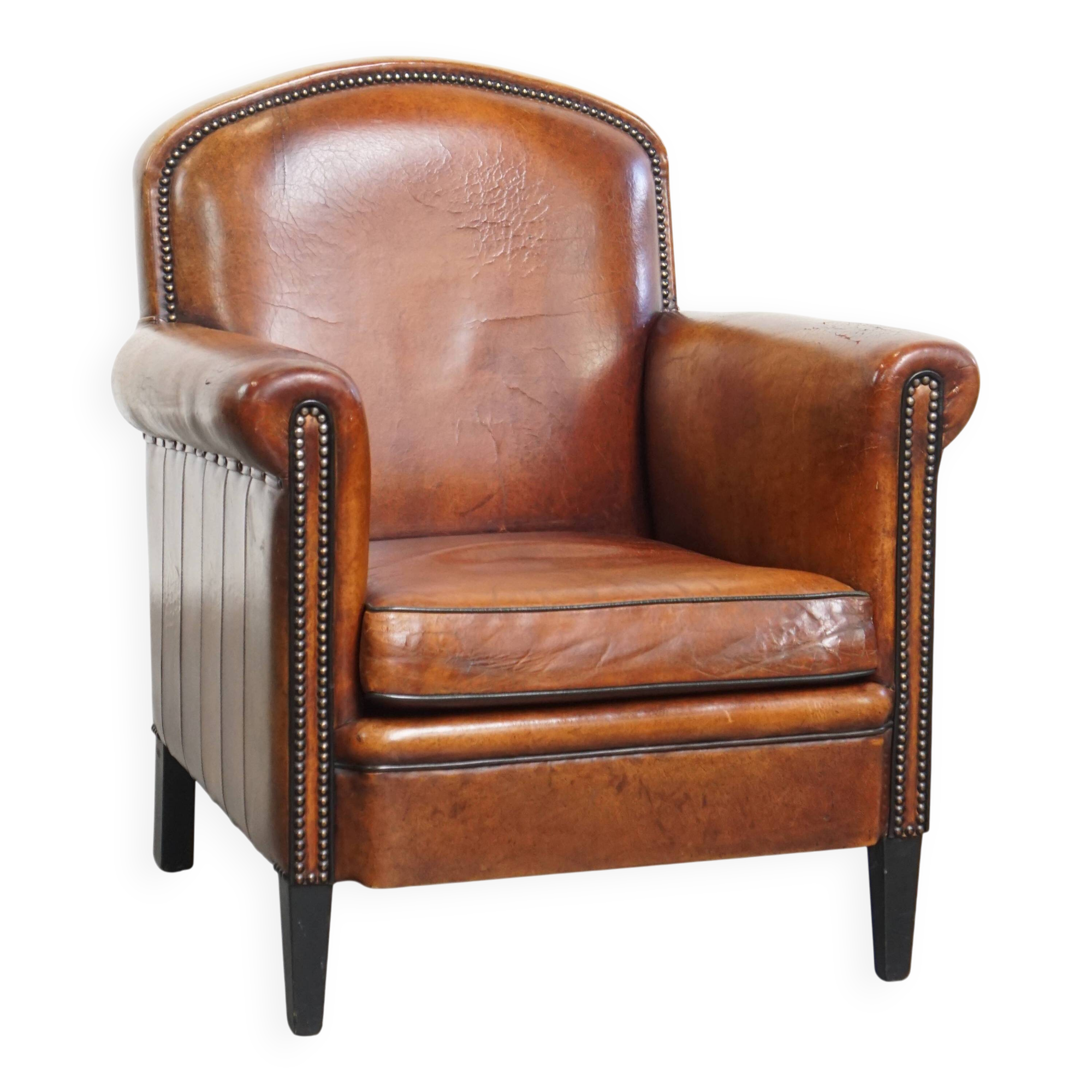 Sheepskin leather armchair in a cognac color with black piping