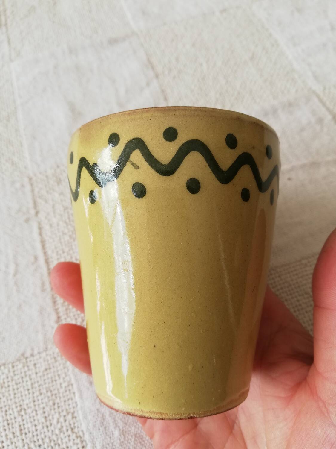 Mustard-colored ceramic cup or glass with green decor