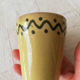 Mustard-colored ceramic cup or glass with green decor