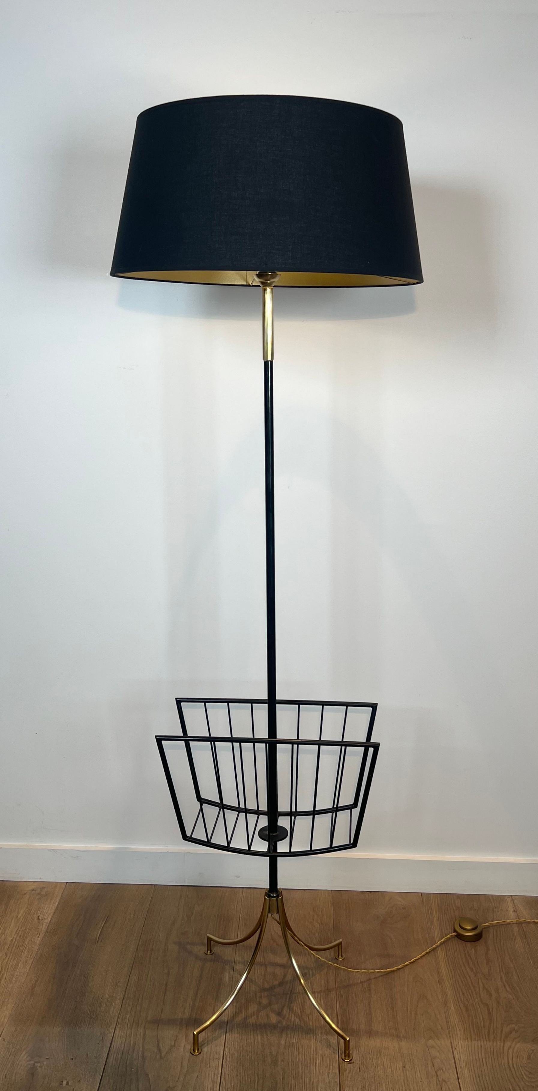 Designer floor lamp in black lacquered metal and brass, incorporating a magazine rack
