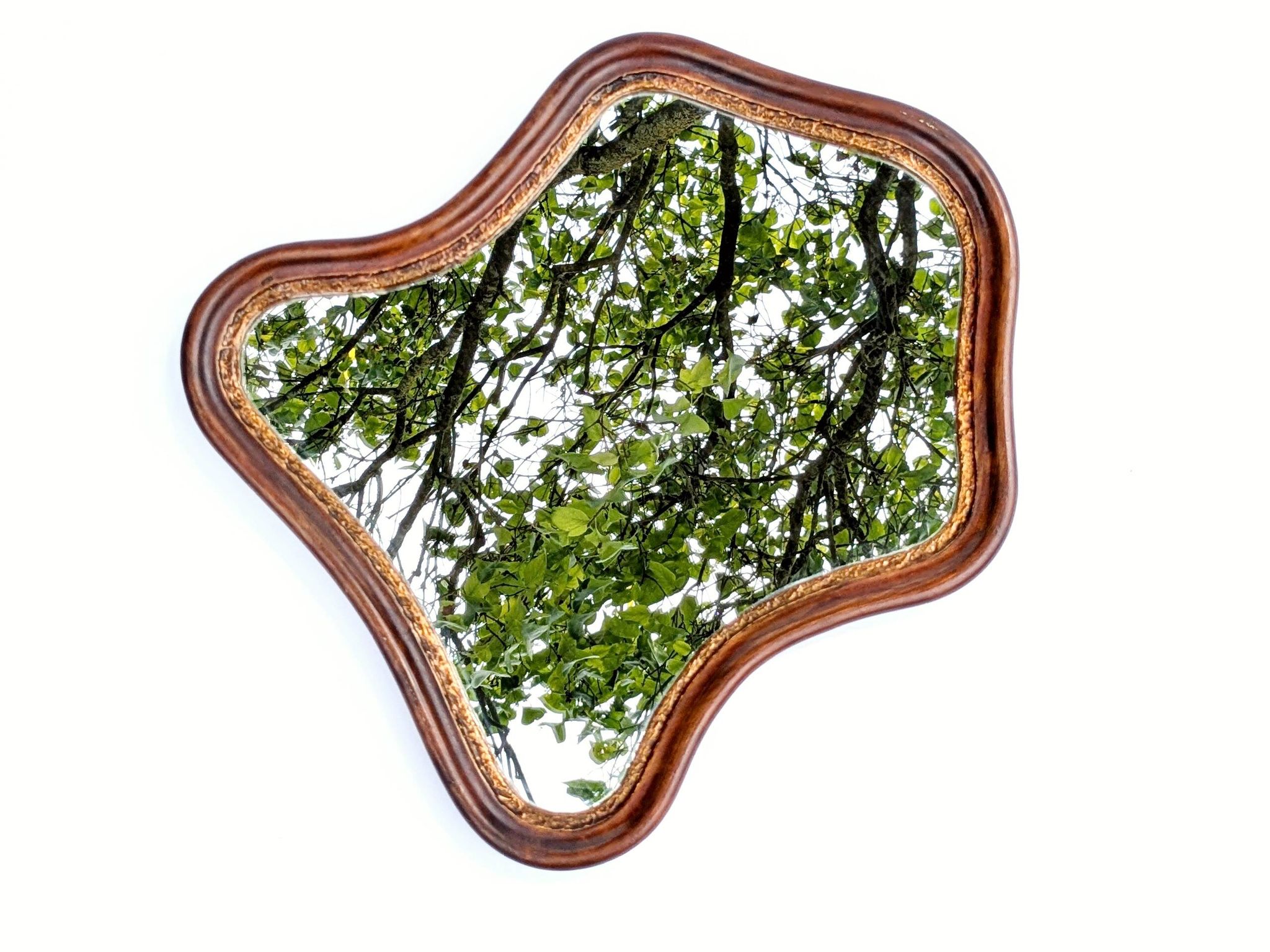 Antique wall mirror in carved wood with a wavy shape and a golden trim.