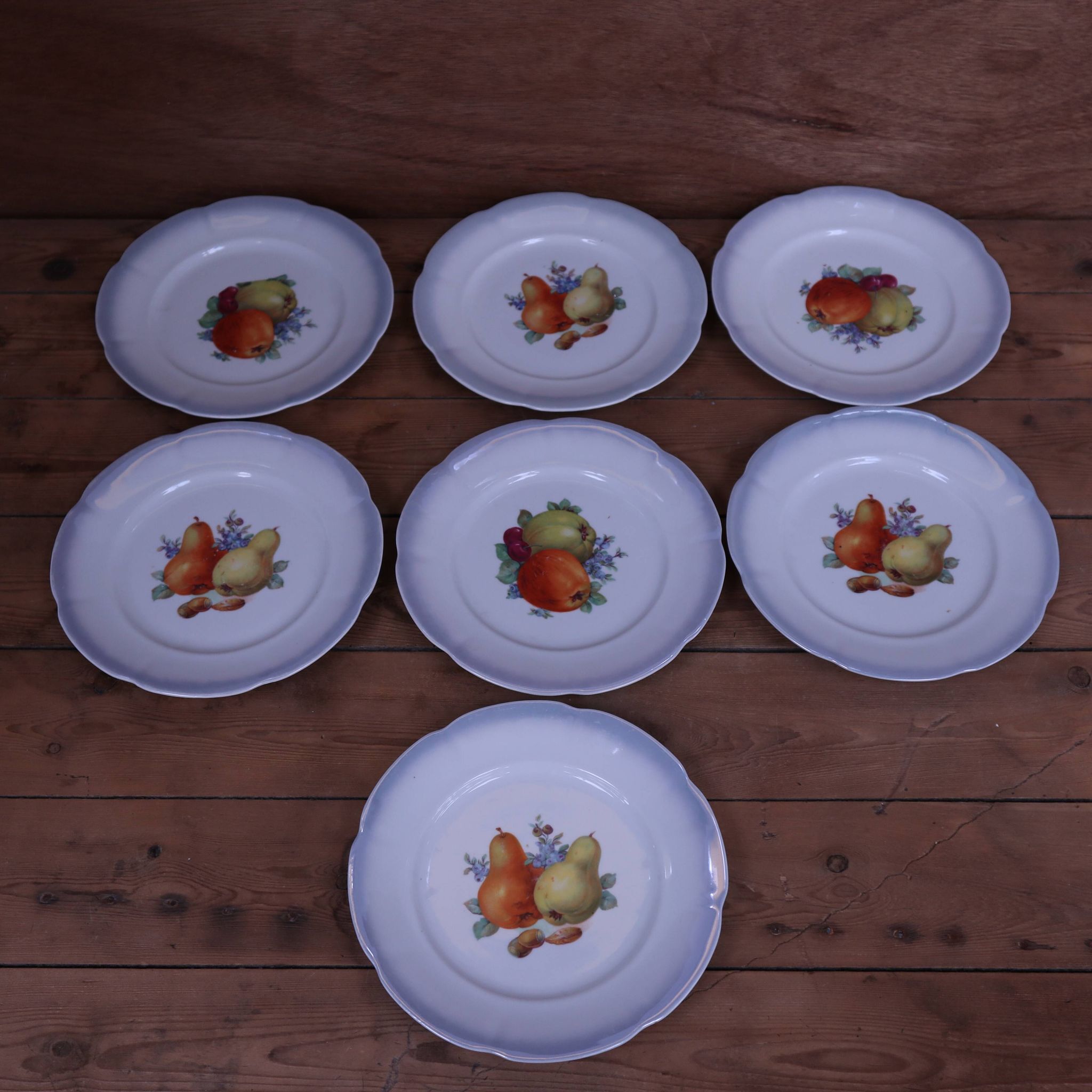 Set of 7 dessert plates and a cake stand with fruit patterns.