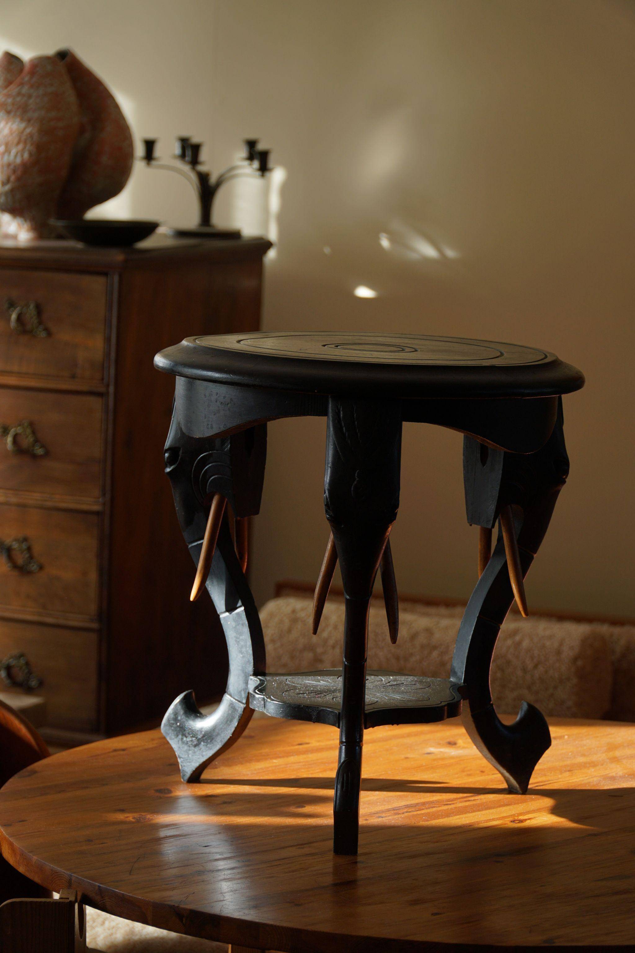 Side table in hardwood ebony with three elephant head-shaped legs, Eastern India, 1920s.
