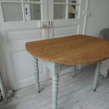 Walnut table with raised flaps, base on verdigris casters.