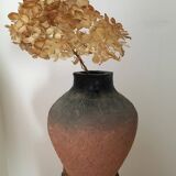 Terracotta vase with gradient of black faded to half on an earth-colored background
