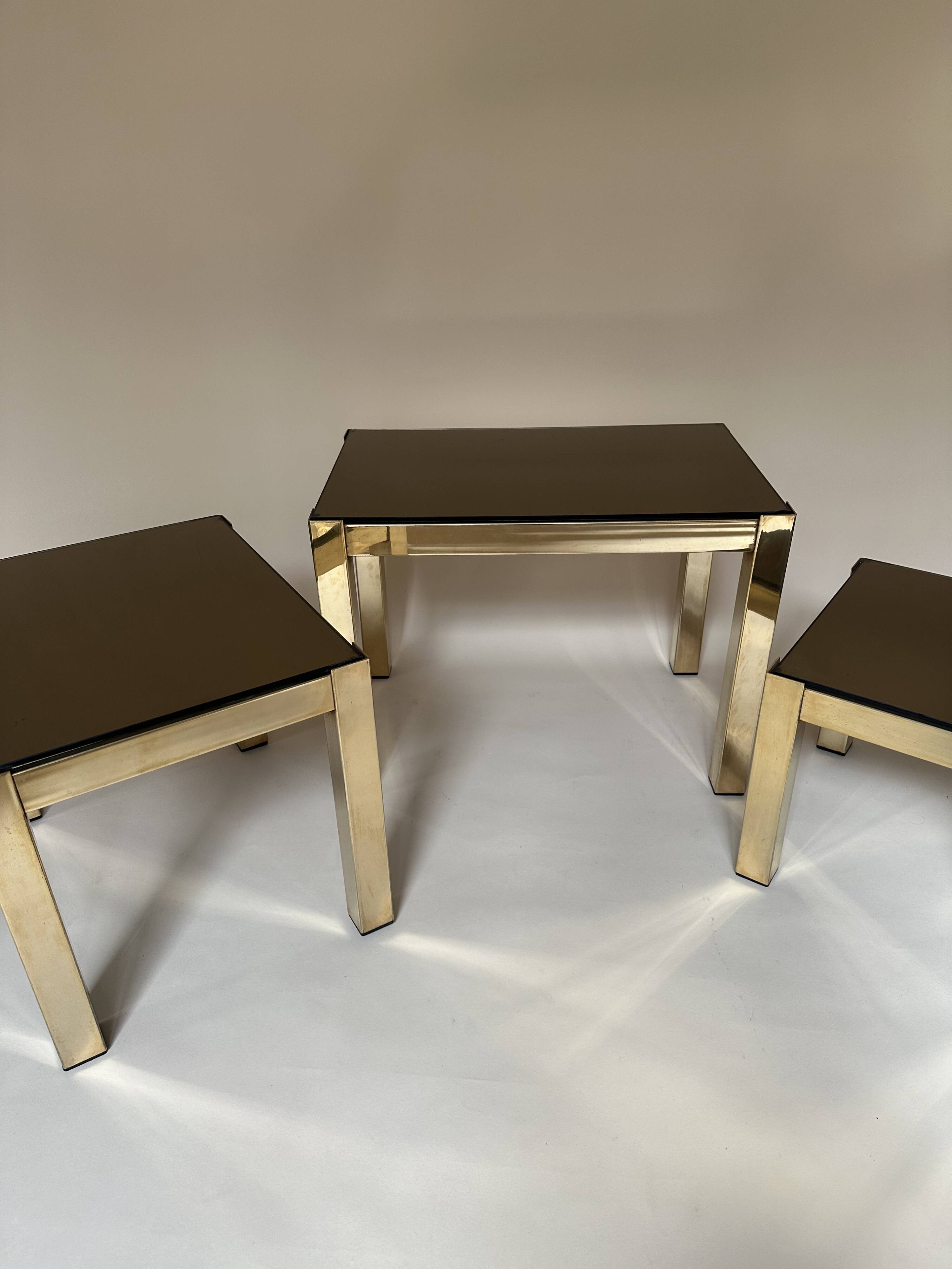 Set of three nesting side tables in brass and smoked mirror.